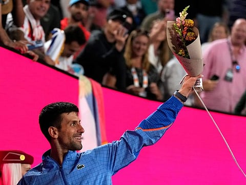 Novak Djokovic of Serbia holds up flowers as he leaves Rod Laver Arena after defeating Andrey Rublev of Russia in their quarter-final.