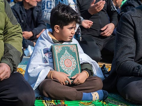 A child holds the Quran during a protest in response to the burning of a copy of the Quran in Sweden, during Friday prayers in Baghdad, Iraq