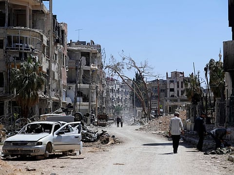Syrians walk through destruction in the town of Douma, the site of a suspected chemical weapons attack, near Damascus, on April 16, 2018.