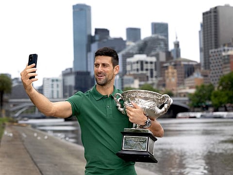 Serbia's Novak Djokovic takes a selfie with the Norman Brooks Challenge Cup next to the boat sheds on the Yarra River, the same spot of his first Australian Open trophy celebrations, in Melbourne.