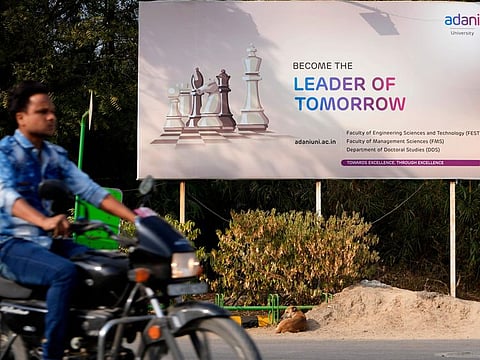 A motorist rides past a hoarding of Adani University near the corporate headquarters of Adani Group in Ahmedabad, India, Friday, Jan. 27, 2023. Shares in India’s Adani Group plunged up to 20% on Friday and the company said it was considering legal action against U.S.-based short-selling firm Hindenburg Research for allegations of stock market manipulation and accounting fraud that have led investors to dump its stocks. (AP Photo/Ajit Solanki)