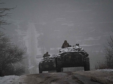 Ukrainian servicemen ride atop BMP-2 infantry combat vehicles driving down an icy road in the Donetsk region on January 30, 2023.