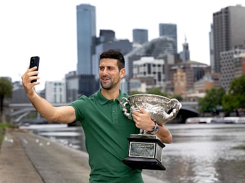 Novak Djokovic takes a selfie with the Australian Open trophy . The Serb will be heading to Dubai.
