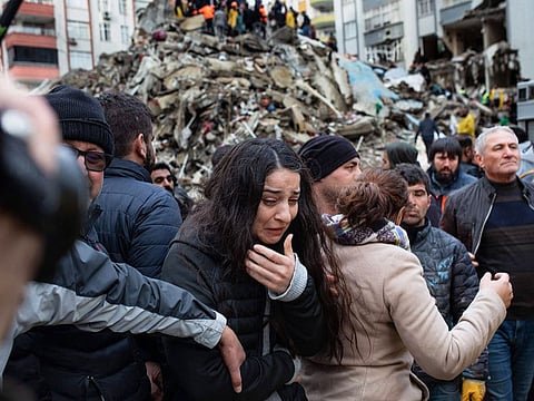 A woman reacts as rescuers search for survivors through the rubble of collapsed buildings in Adana.