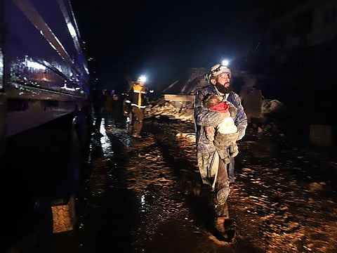A member of the Syrian civil defence carries a child rescued from the rubble following an earthquake in the town of Zardana in the countryside of the northwestern Syrian Idlib province.