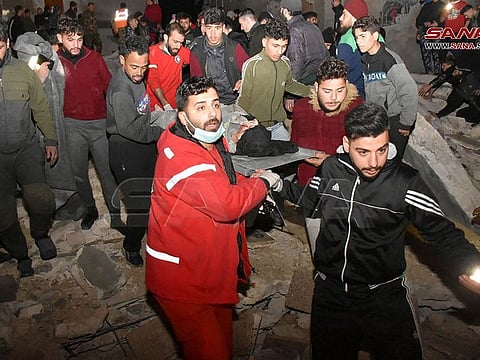 In this handout photo taken by Sana news aganecy in Hama, Syria on February 6, 2023, rescuers evacuate a victim from an eight-storey building that collapsed after an 7.8-magnitude earthquake in southern Turkey.