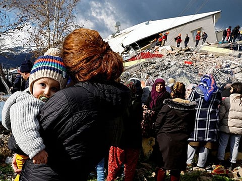 A woman holds a child as she stands near rubble and damages following an earthquake in Gaziantep, Turkey
