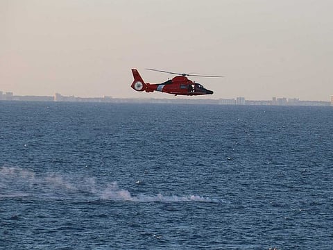 In this handout image courtesy of the US Navy a US Coast Guard helicopter flies over a debris field during recovery efforts of a high-altitude surveillance balloon in the Atlantic ocean on February 4, 2023.
