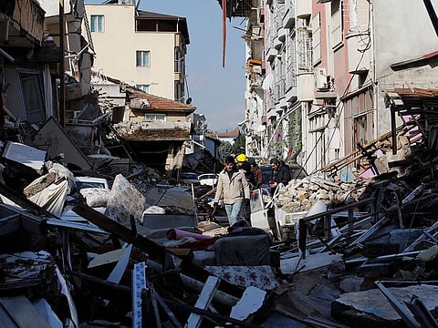 People walk amid the rubble in the aftermath of a deadly earthquake in Hatay, Turkey, February 8, 2023.