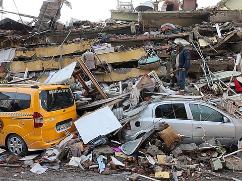 People inspect the damage as rescuers search for survivors in the aftermath of a deadly earthquake in Hatay, Turkey.