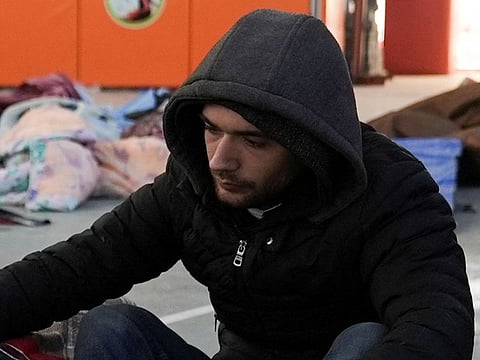 Yunus Emre Kaya sits in a sports hall where relatives are identifying their loved ones.