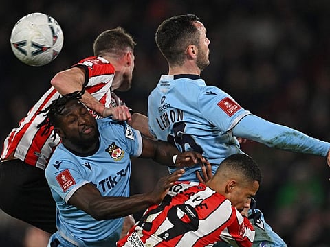 Wrexham's Jacob Mendy (left) and teammate Harry Lennon (top right) vie for the ball against Sheffield United's Iliman Ndiaye (bottom right) during the English FA Cup fourth round-replay at Bramall Lane in Sheffield, northern England.