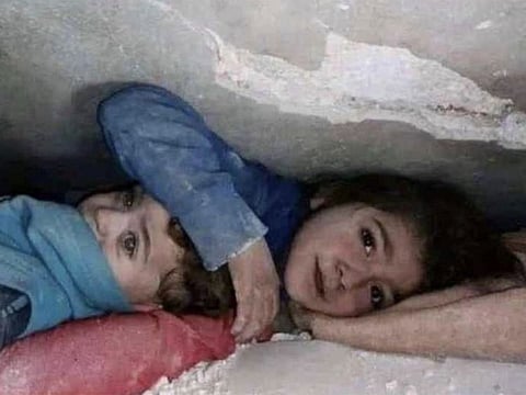 A photo of a seven-year-old girl shielding her younger brother under the quake rubble has gone viral