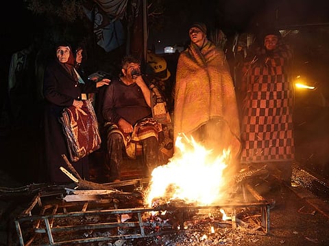 People warm themselves around a bonfire in the rubble in Kahramanmaras, Turkey