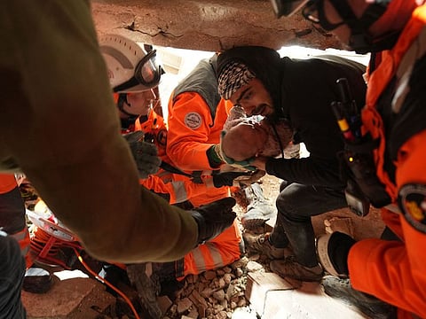 Members of the Swiss rescue team handing over a four-month-old girl called Abir rescued from under the rubble of a collapsed building following a massive earthquake on February 6, in Antakya in Hatay.