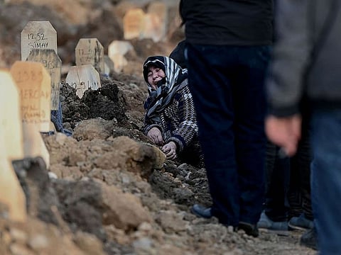 A woman mourns over the grave of her loved ones during a funeral in Kahramanmaras.