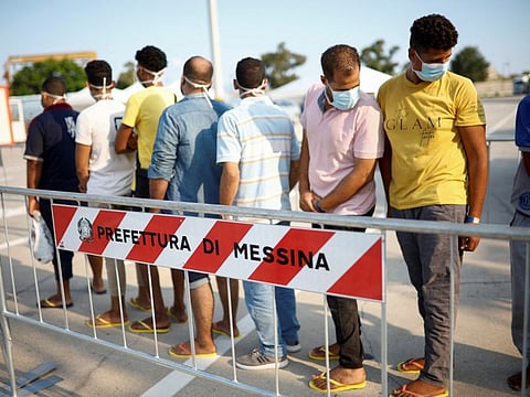 Migrants queue after disembarking from Open Arms rescue boat after arriving at Messina port, Sicily, Italy.