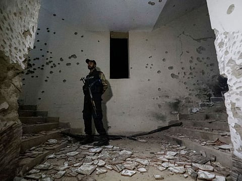 A police officer secures a site as he stands amid the damage in the aftermath of an attack on a police station in Karachi on February 17, 2023.