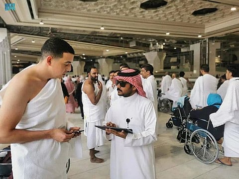 Saudi employees talk to pilgrims during Umrah surveys.