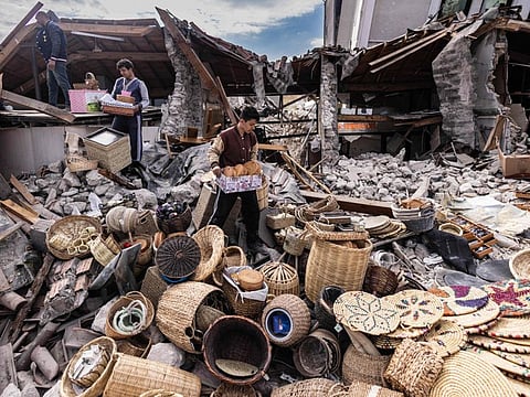 Mustafa Ozdimir (C) helps his family as they collect goods from their collapsed shop in the city of Antakya on February 19, 2023.