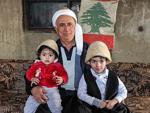 Hatmaker Youssef Akiki poses for a picture with his daughter and nephew as they wear traditional "Labbadeh" hats at his workshop in the mountain village of Hrajel in Keserwan-Jbeil province on February 14, 2023.