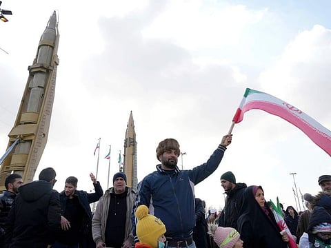 A man waves an Iranian flag as domestically built missiles are displayed at background during the annual rally commemorating Iran's 1979 Islamic Revolution, in Tehran, on Feb. 11, 2023.