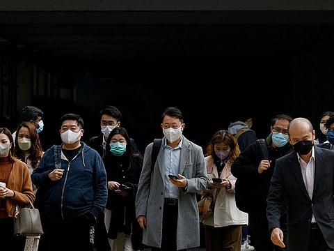 People wear face masks on the street, a day before government scraps the mask rule in Hong Kong.