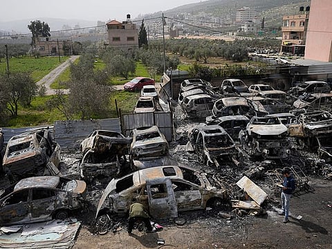 Palestinians inspect scorched cars in a scrapyard, in the town of Hawara, near the West Bank city of Nablus, on February 27, 2023. Scores of Israeli settlers went on a violent rampage in the northern West Bank, setting cars and homes on fire after two settlers were killed by a Palestinian gunman.