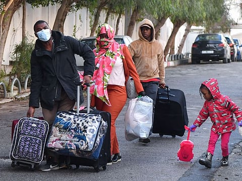 Sub-Saharan migrants head with their belongings to a bus taking them to a repatriation flight, leaving Tunis for their countries of origin on March 4, 2023.