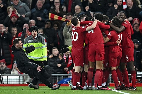 A pitch invader (left) slips and collides with Liverpool players celebrating their seventh goal during the English Premier League match against Manchester United at Anfield in Liverpool.