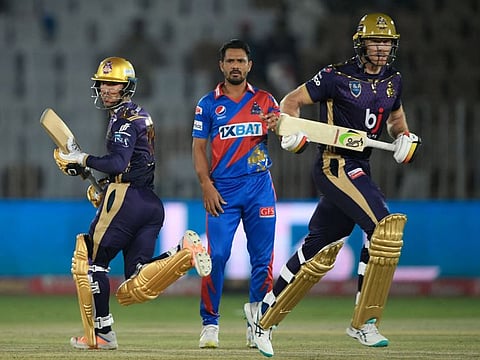 Quetta Gladiators' Omair Bin Yousuf (left) and teammate Martin Guptill (right) run between the wicket as Karachi Kings'Aamer Yamin watches on during the Pakistan Super League (PSL) T20 cricket match at the Rawalpindi Cricket Stadium, in Rawalpindi.