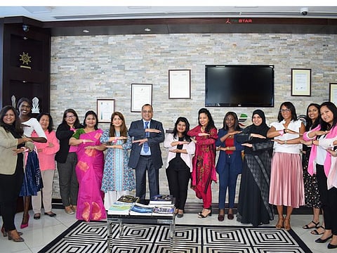 Tristar Group CEO, Eugene Mayne poses with head-office-based women staff on March 8, 2020