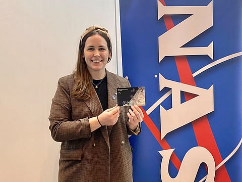 Kate Manning shows NASA-USGS lenticular post card on “Dubai from space” at NASA stand at the SpaceOps 2023 in Dubai