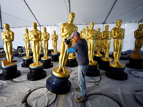 A worker moves an Oscar statue before being placed out for display in Los Angeles, California