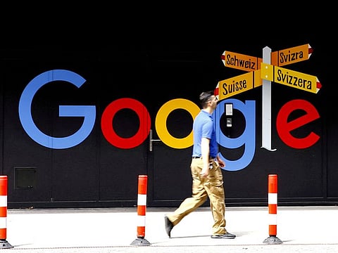 A man walks past a logo of Alphabet Inc's Google in front of an office building in Zurich, Switzerland