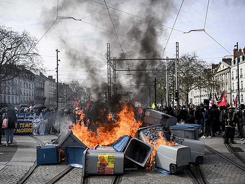 Garbage bins are set on fire by protestors during a demonstration on a 8th day of strikes and protests across the country against the government's proposed pensions overhaul in Nantes on March 15, 2023.