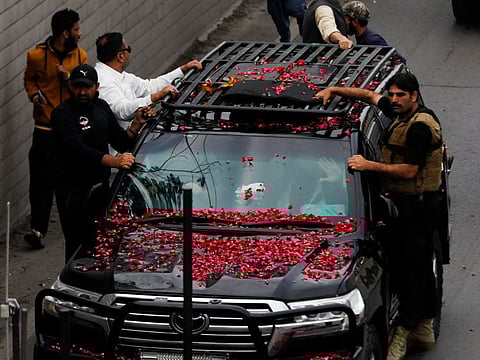 Former Pakistani Prime Minister Imran Khan, waves from the vehicle as he leaves from Lahore to appear before Islamabad High Court, in Lahore on March 18, 2023.