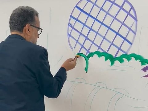 Ayman Awwad, who is from Jordan, seen painting at Sheikh Shakhbout Medical City in the UAE capital in this still from a video