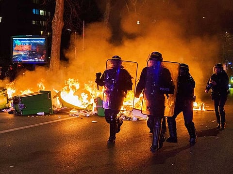 Riot police run past a fire lit by demonstrators on Boulevard Massena during a protest against pension reformat at Porte de Choisy in Paris, France, on Saturday, March 18, 2023.