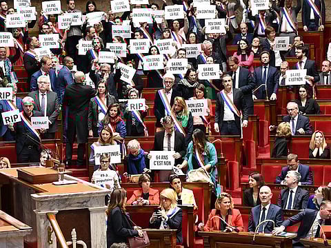 Members of National Assembly parliamentary group La France Insoumise (LFI) and left-wing coalition NUPES (New People's Ecologic and Social Union) hold signs reading "64 is a no", "See you in the street" next to France's Prime Minister Elisabeth Borne (1R) and French Labour Minister Olivier Dussopt (2R) after the vote of one motion of no confidence at the French National Assembly
