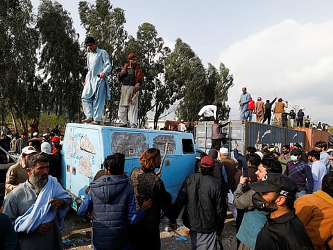 Supporters of former Pakistani Prime Minister Imran Khan climb on shipping containers, placed to block the road, during a clash outside the federal judicial complex in Islamabad, Pakistan March 18, 2023.