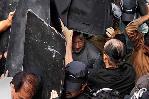Security personnel hold bulletproof shields to secure former Prime Minister Imran Khan, centre, after appearing in a court, in Lahore, on March 21, 2023.