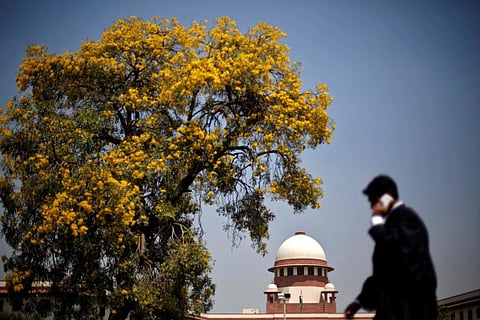 A lawyer speaks on his mobile phone as he walks past India's Supreme Court in New Delhi, April 1, 2013.