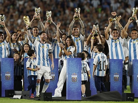 Argentina's Lionel Messi and teammates celebrate with their families with the World Cup replica on Thursday.