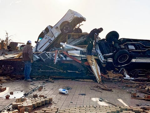 Law-enforcement officers climb through debris on a diner looking for survivors early Saturday, March 25, 2023 in Rolling Fork, Mississippi.