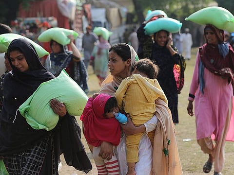 People leave after collecting free bags of flour from a government distribution point in Multan.