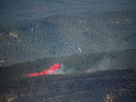 A plane throws water over a wildfire in Pina de Montalgrao, Castellon, in eastern Spain, March 26, 2023.