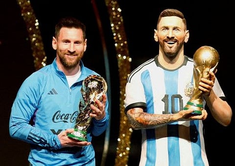Argentina's Lionel Messi (left) poses with a statue of himself holding the World Cup during the Conmebol event at the Conmebol headquarters, Luque, Paraguay.