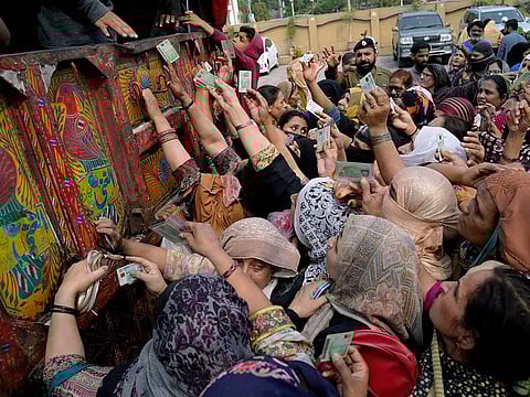 Women show their identity cards to receive a free sack of wheat flour at a distributing point, in Lahore, Pakistan, Monday, March 20, 2023.