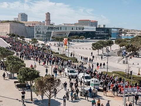 Demonstrators march during a protest against pension reform, backdropped by 'La Villa Mediterranee' building in Marseille, France, on Tuesday, March 28, 2023.